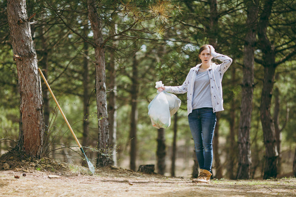Young shocked woman cleaning rubbish holding trash bags and clin - Foto, immagini