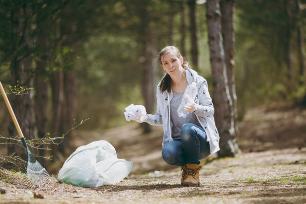 Молода жінка в повсякденному одязі, рукавички прибирають сміття в трасу
 - Фото, зображення