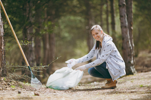 Young smiling woman in casual clothes, gloves cleaning rubbish i - Foto, afbeelding