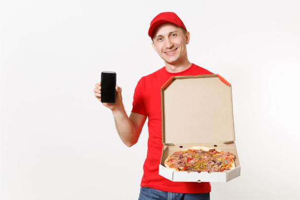 Dostawy, uśmiechnięty człowiek w mundurze czerwony na białym tle. Mężczyzna ' Pizzaman ' Kurier w WPR, telefon komórkowy gospodarstwa t-shirt z puste pusty ekran, włoska pizza w tekturowe flatbox. Miejsce. - Zdjęcie, obraz