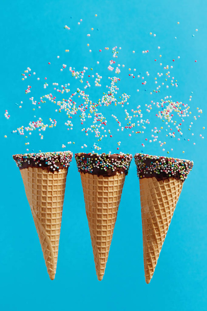 Ice cream cones with colorful sprinkles on blue background.  - Фото, зображення