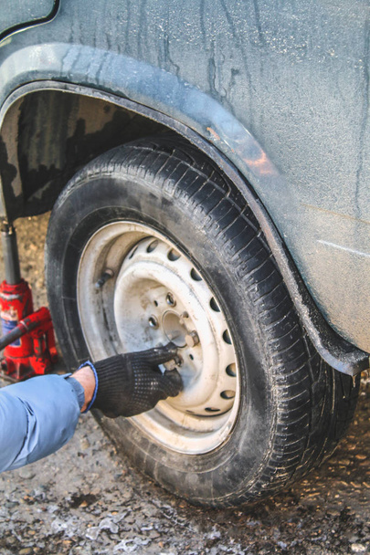 Sustitución de tuercas de arrastre a mano mientras se cambian los neumáticos en un vehículo
. - Foto, Imagen