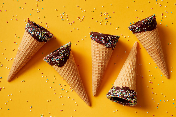 Ice cream cones with colorful sprinkles on yellow background.  - Photo, Image