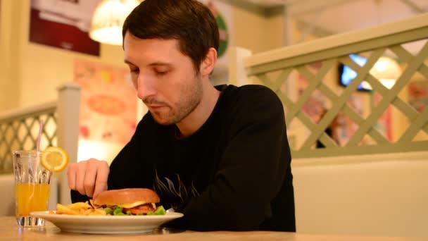 Un hombre tiene una hamburguesa en un restaurante y bebe limonada
 - Imágenes, Vídeo