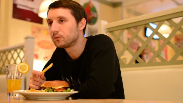 Ένας άντρας έχει ένα Burger σε ένα εστιατόριο και πίνει λεμονάδα - Πλάνα, βίντεο