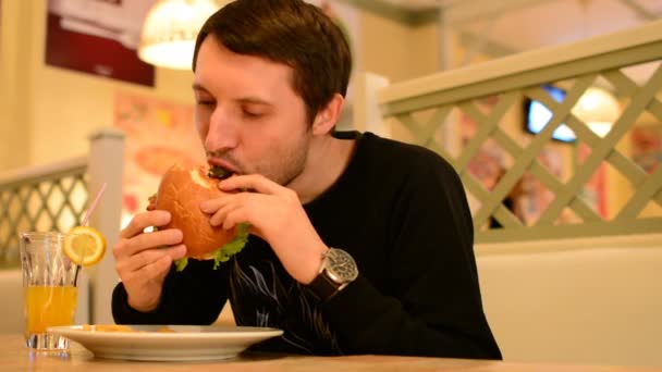 Un hombre tiene una hamburguesa en un restaurante y bebe limonada
 - Metraje, vídeo