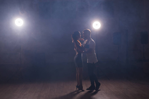 Geschickte Tänzer, die im dunklen Raum unter dem Licht und Rauch des Konzerts auftreten. sinnliches Paar, das einen künstlerischen und emotionalen zeitgenössischen Tanz aufführt - Foto, Bild