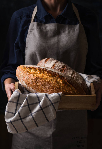 Baker holding fresh homemade bread - Фото, изображение