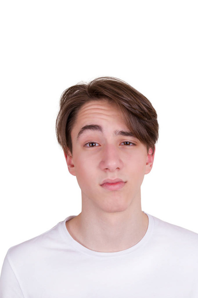 Doubting or surprised young man. Portrait of teenager in white T-shirt, isolated on white background - Valokuva, kuva