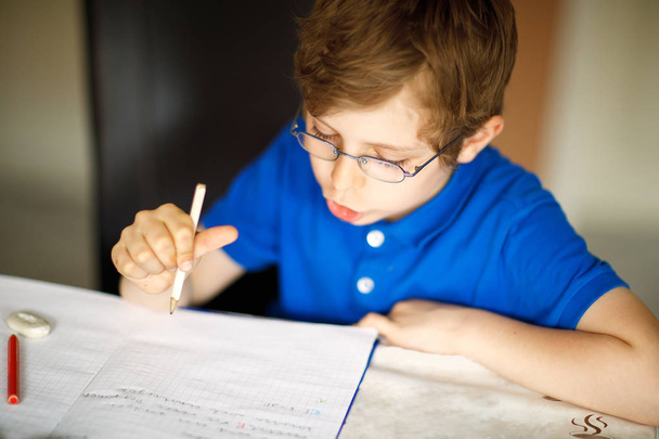 Cute little kid boy with glasses at home making homework, writing letters with colorful pens. - Photo, Image