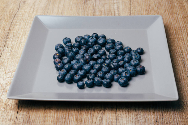 large, fresh blueberries lie on a gray plate, close-up - Fotoğraf, Görsel