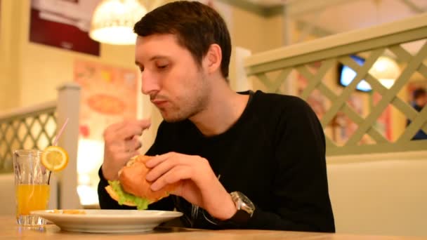 Un hombre tiene una hamburguesa en un restaurante y bebe limonada
 - Imágenes, Vídeo