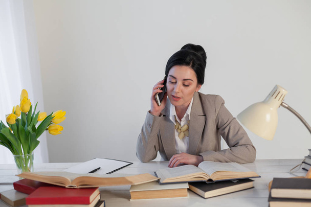 ofiste telefonda konuşurken iş elbiseli esmer kadın - Fotoğraf, Görsel