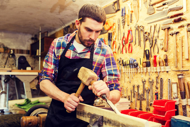 carpenter with wood, hammer and chisel at workshop - Fotó, kép