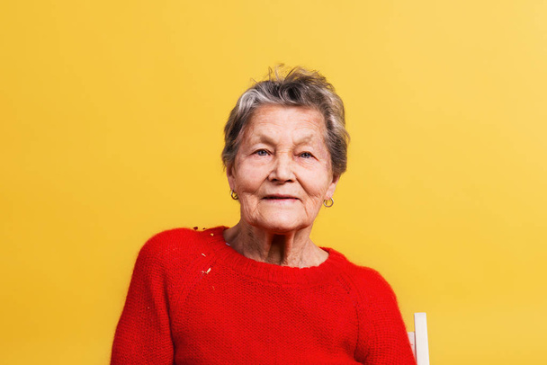 Portrait of a senior woman in studio on a yellow background. - Foto, afbeelding
