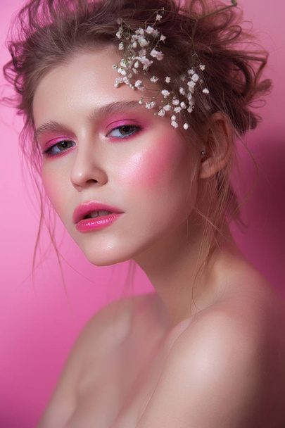 young girl with pink make-up. beauty close-up on pink background. messy hair with white flowers. healthy glowing skin - 写真・画像