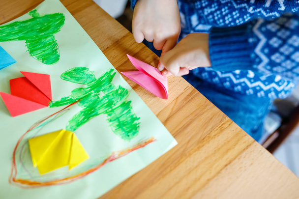 Gros plan des mains du petit enfant faisant origami de fleurs de tulipe pour une carte postale pour la fête des mères ou anniversaire. - Photo, image