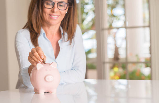 Mujer de mediana edad con moneda de alcancía, ahorro y concepto de dinero
, - Foto, imagen
