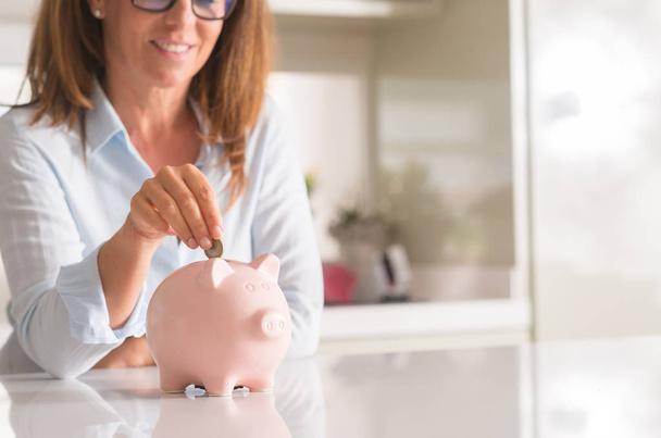 Femme d'âge moyen avec pièce de monnaie tirelire, concept d'épargne et d'argent
, - Photo, image