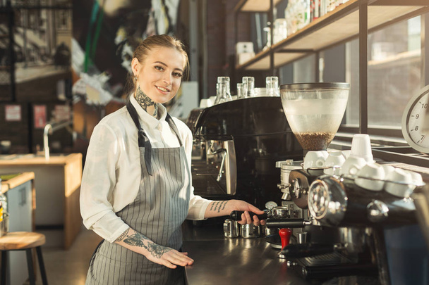 Tattooed barista making coffee in professional coffee machine - Фото, изображение