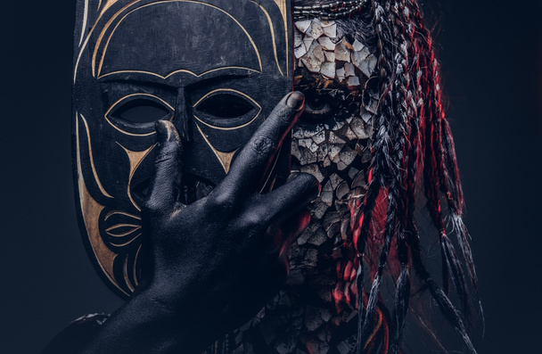 Gros plan portrait d'une sorcière de la tribu indigène africaine, vêtue d'un costume traditionnel. Concept de maquillage. Isolé sur un fond sombre
. - Photo, image