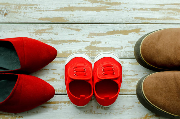 zwei rote Schuhe oder Turnschuhe von Mutter oder Vater und Kind auf Holz - Foto, Bild
