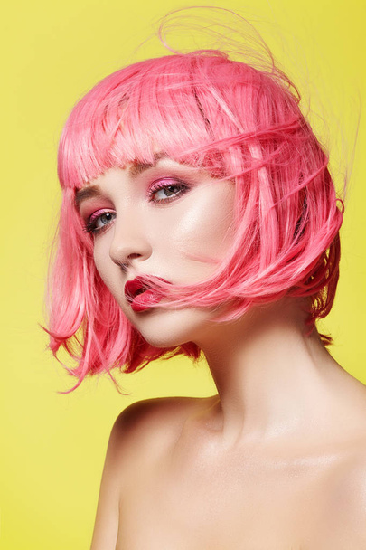 Young woman in pink wig. Beautiful model with fashion makeup. Bright spring look. Sexy hair color, medium hairstyle - Foto, afbeelding
