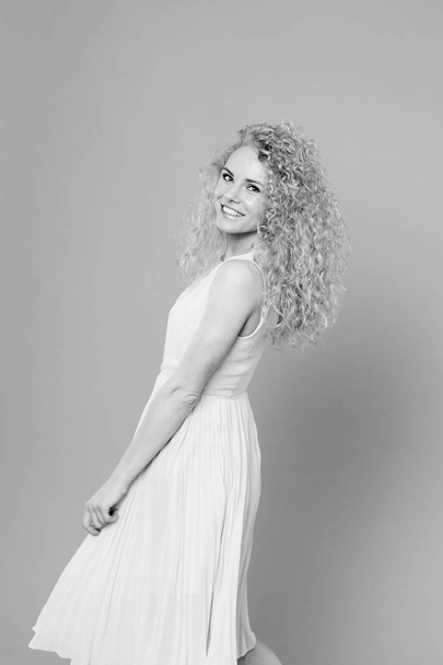 Portrait of a pretty curly blonde woman, wearing light dress - Foto, Imagen