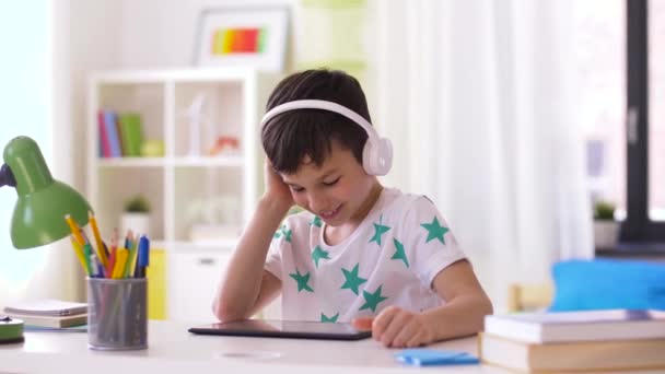little boy with tablet pc and headphones at home - Video