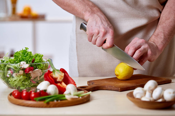 Man cooking at kitchen making healthy vegetable salad, close-up, selective focus. - 写真・画像