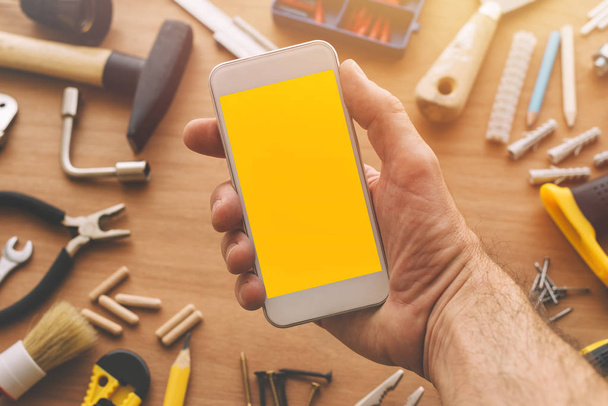 Handyman holding smart phone with blank screen in hand - Photo, Image