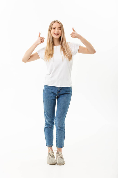 Lifestyle Concept: Happy smiling young woman in jeans looking at the camera giving a double thumbs up of success and approval isolated on white - Photo, image