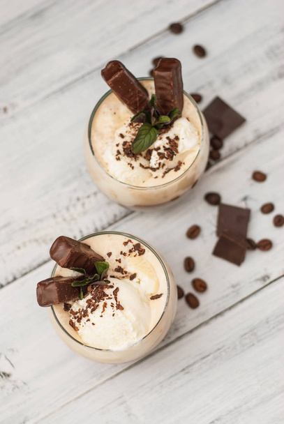 Iced Mocha Frappe Coffee with Whip Cream, Summer Drinking times. Coffee Beans. rustic textured Wooden Background. Mint Leaves - Фото, изображение