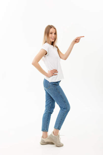 Lifestyle Concept: Portrait woman pointing or pushing something with index finger. Beautiful casual young woman isolated on white background in full length standing in profile. - Fotografie, Obrázek