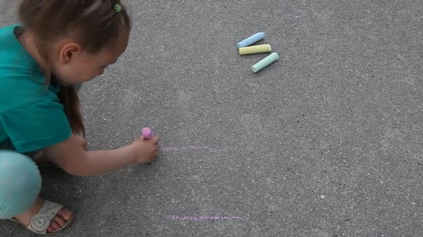 Παιδί κορίτσι εφιστά με χρωματιστά κιμωλία στο πεζοδρόμιο άσφαλτο κοντά επάνω εξωτερική - Πλάνα, βίντεο