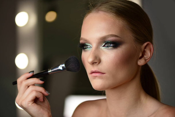 Beautiful teenage girl applying cosmetic powder on face with tassel, skin care concept. - Φωτογραφία, εικόνα