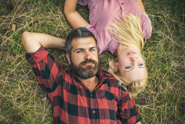 Couple in love relax on green grass. Bearded man and woman with long blond hair. Hipster and girl enjoy summer day on nature. Summer vacation concept. Love romance and family. - Photo, image