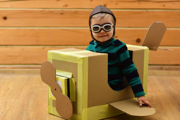 Little boy child play in cardboard plane, childhood. Dream, career, adventure, education. Pilot travel, airdrome, imagination. Air mail delivery, aircraft construction. Kid, pilot school, innovation. - Фото, изображение