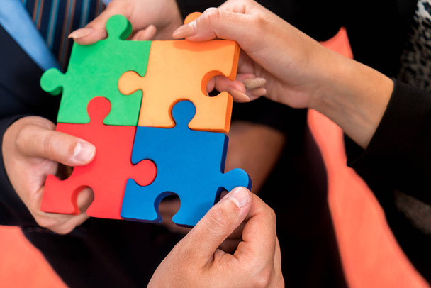 Деловые люди решают головоломку. Команда держит в руках разноцветные кусочки головоломки
 - Фото, изображение