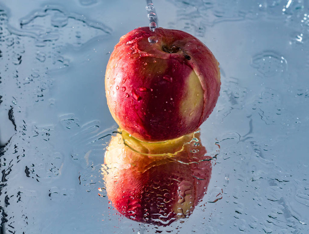 Lavare una mela rossa con riflesso e con spruzzi e gocce d'acqua
 - Foto, immagini