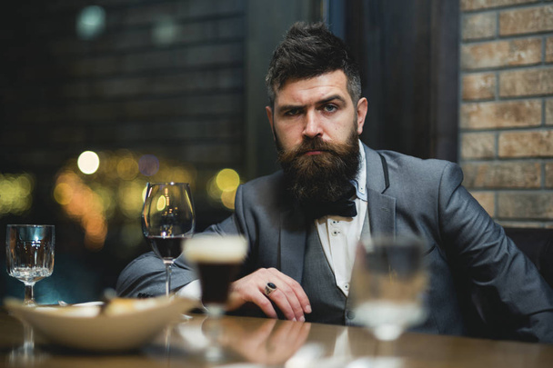 Concept photo of rich people luxury life. Adult successful elegant businessman wearing suit and drinking wine in luxury restaurant - Φωτογραφία, εικόνα