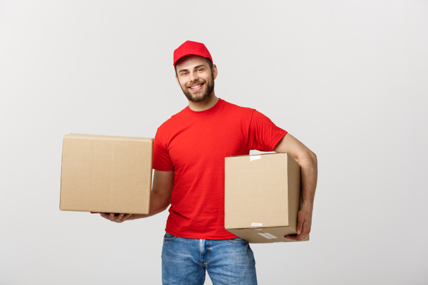 Delivery Concept: Smiling handsome caucasian delivery man holding a paper box. Isolated over grey background. - Foto, Imagen