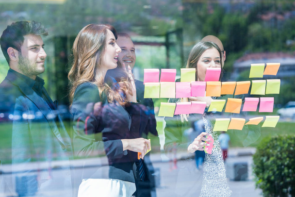 business, startup, planning, management and people concept - happy creative team with stickers on office glass board talking at office - Fotoğraf, Görsel