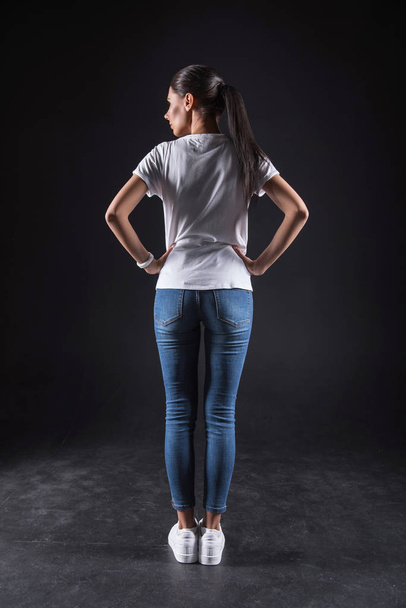 Confident young woman standing against black background - Foto, immagini