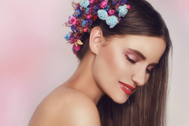 Beautiful young woman with delicate flowers in their hair. Beauty Girl with Flowers Hairstyle.Model portrait with Summer pink and blue Flowers. Hairstyle with flowers. Fantasy portrait in pink. Smile. - Fotoğraf, Görsel