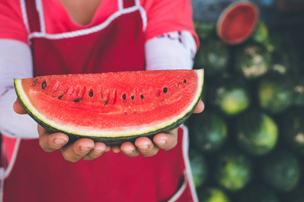 Hands holding piece of fresh red slice watermelon on the heap ba - Fotografie, Obrázek