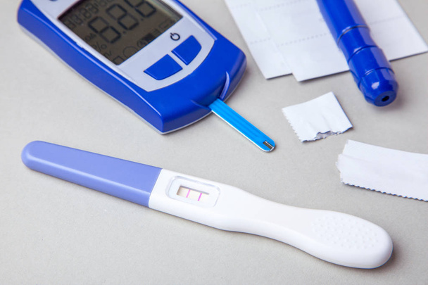 Diabetes mellitus, aumento do açúcar no sangue em mulheres grávidas. Glucometer e teste positivo para variabilidade. Fundo cinzento
 - Foto, Imagem