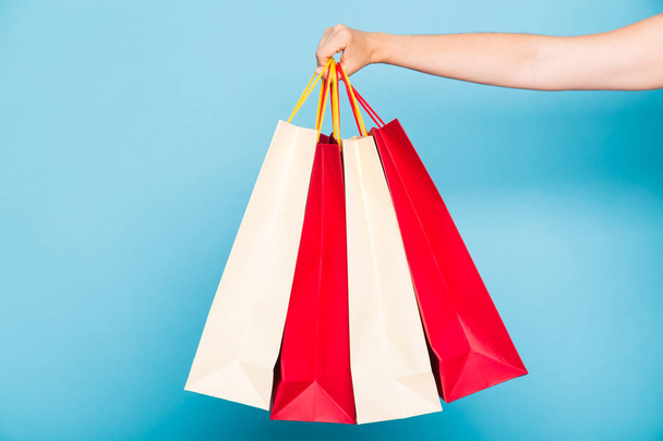 people, sale and consumerism concept - close up of female hand with shopping bags over white background - Фото, изображение