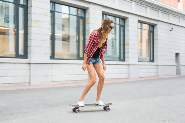 Beautiful young hipster woman with skateboard outdoors - Photo, Image
