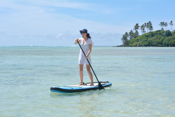 Mujer joven en un stand up paddle board paddle boarding
 - Foto, imagen